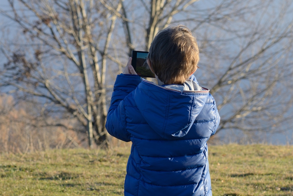 Child Standing Outdoors Holding Tablet